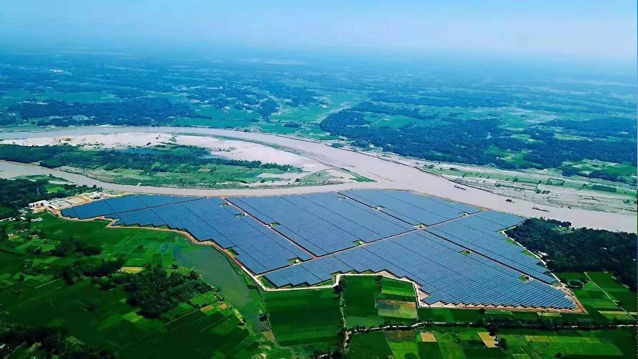 Aerial view of a utility-scale solar photovoltaic plant beside a river in rural Bangladesh